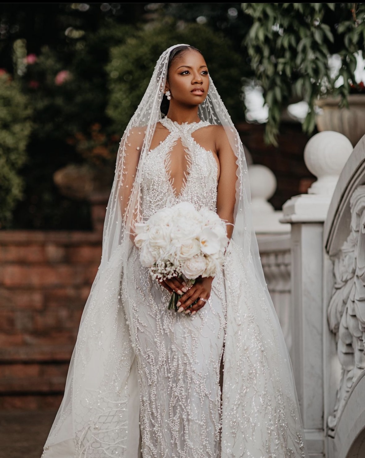 Bride in a beaded gown and cathedral veil holding a white bouquet